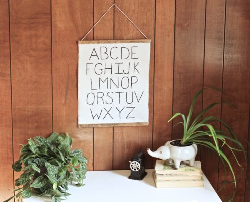 homemade canvas alphabet sign hanging above a white wooden kids desk