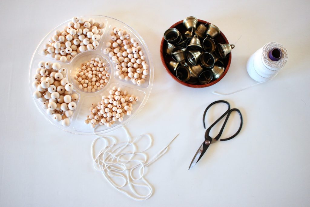 Supplies needed to make a wood bead Christmas Garland and a Brass Bell Christmas Garland. 