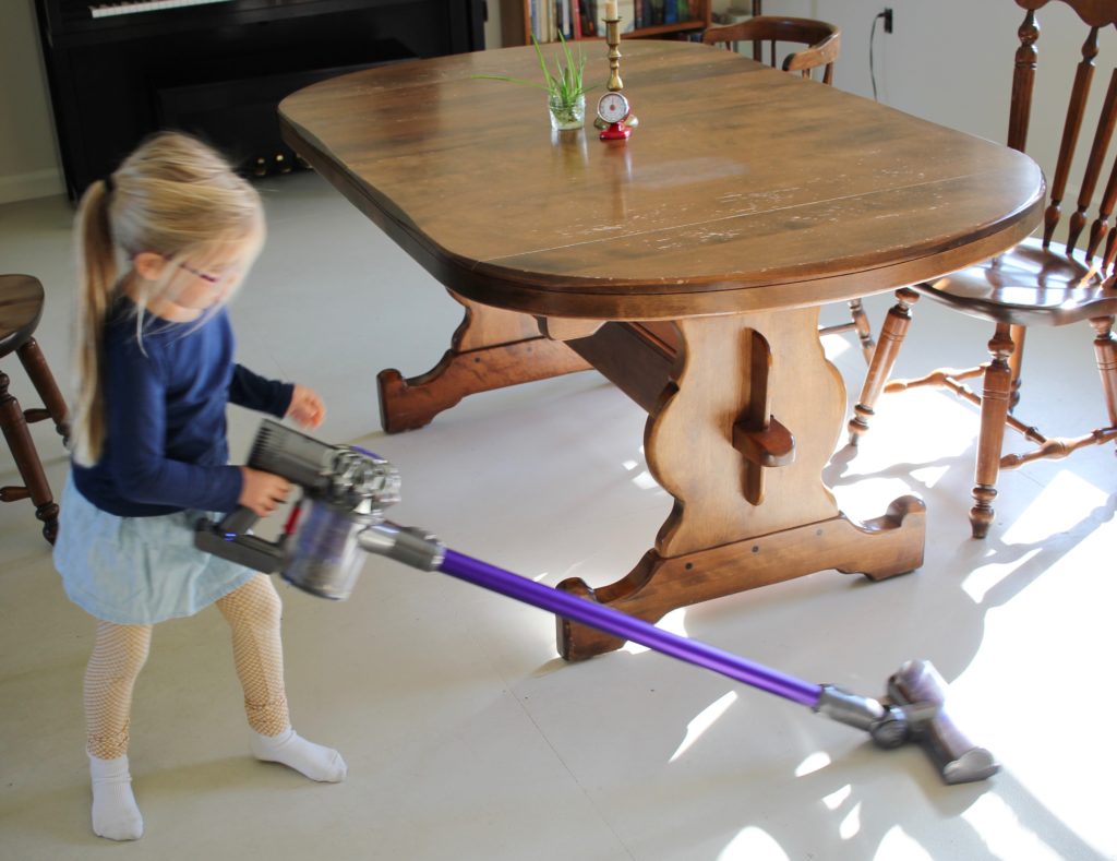 Vacuuming up the crumbs under the table is a simple chore to start having your child do at a young age.