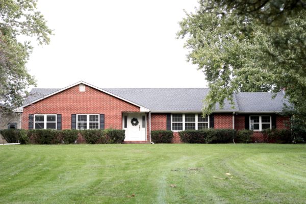 This House of Dreams - Farmhouse Ranch - Farm Living, Homemaking and Motherhood - Farmhouse Tour Before Renovations: brick ranch house with black shutters and a white door