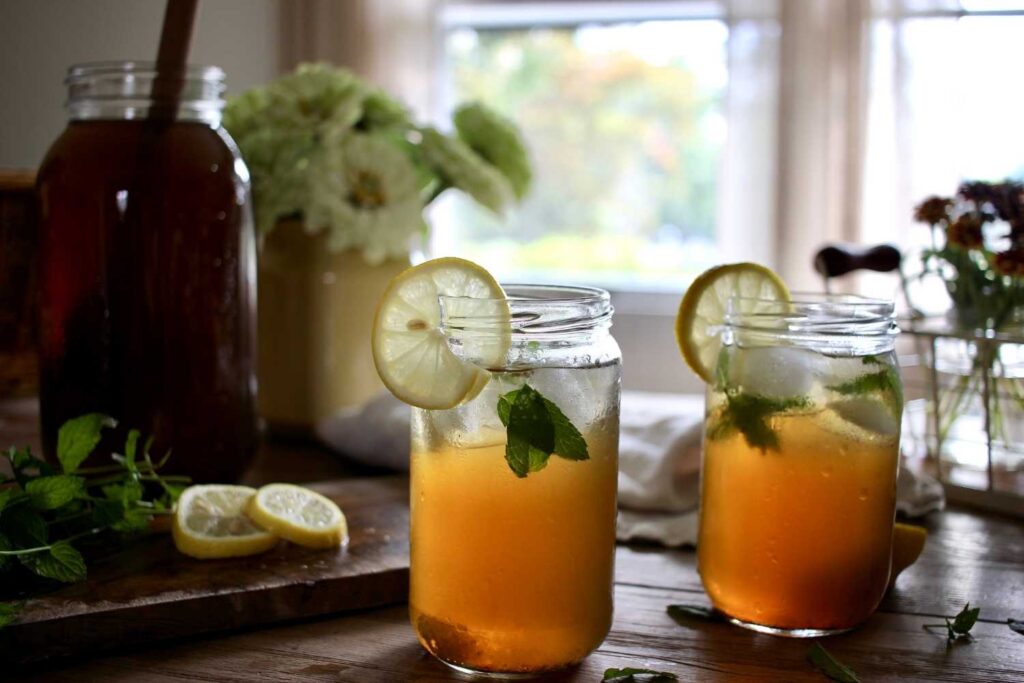 Two glasses with lemon slices on the side filled with nettle iced tea. 