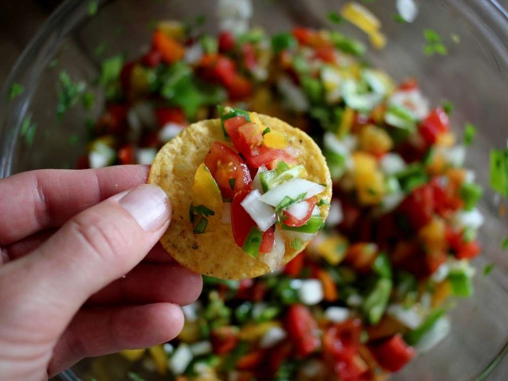 Homemade garden fresh salsa with tomatoes, peppers, onion, garlic, cilantro, lime and salt on a corn chip.