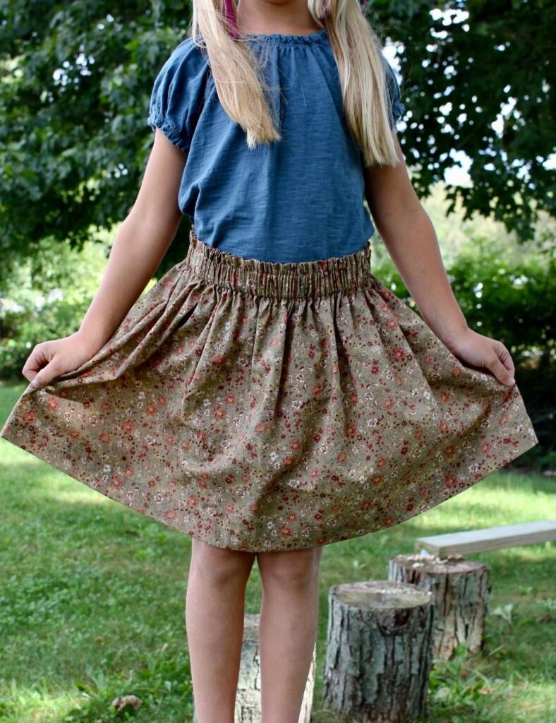 A young girl wearing brown floral simple elastic waist skirt with a ruffle top.