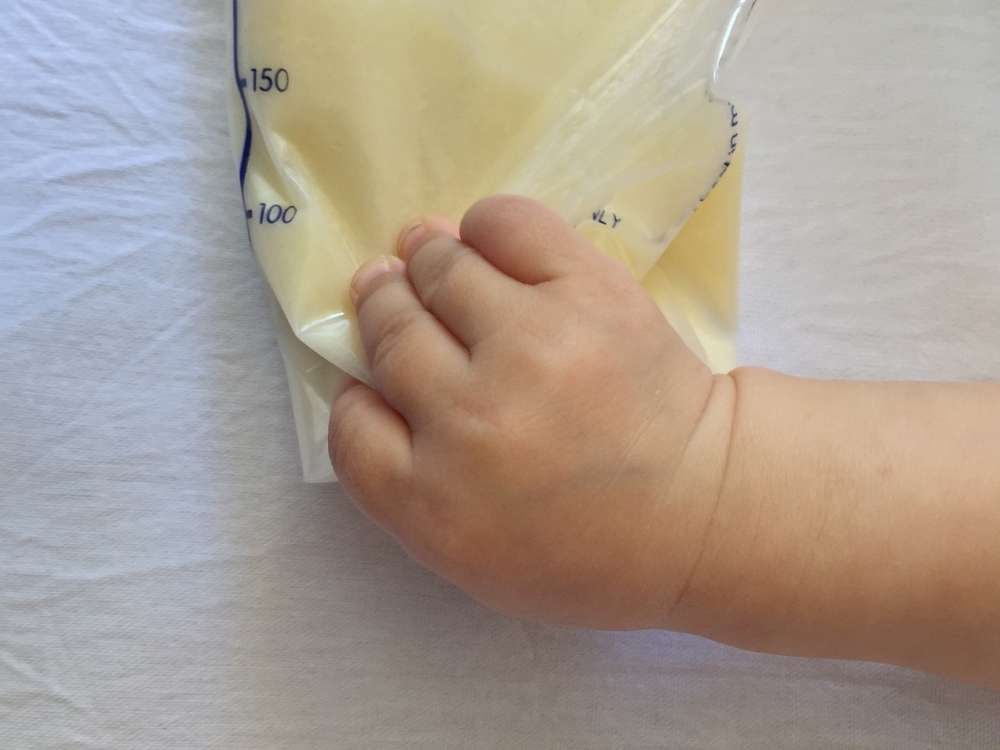 A baby's hand on a bag of breastmilk.
