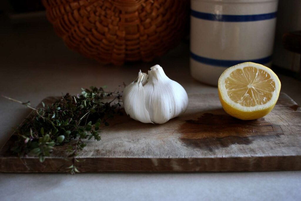 thyme, garlic and lemon sitting on a wood cutting board