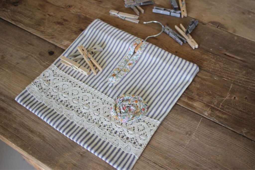A simple ticking striped clothespin bag laying on a wood table with clothespins scattered around