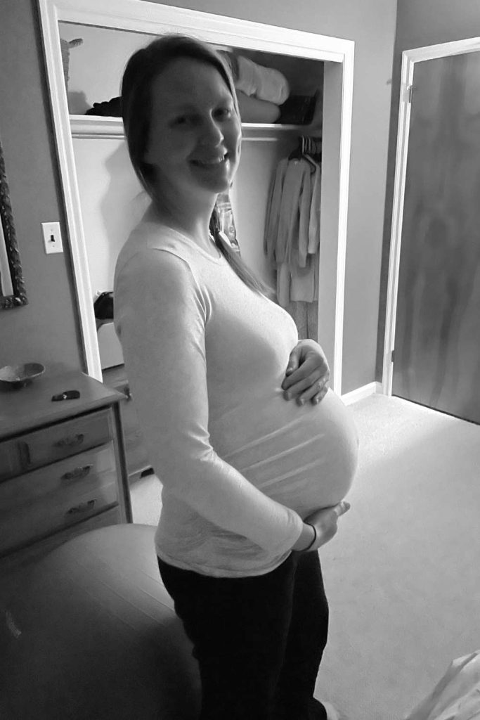Pregnant woman in labor holding her belly smiling at the camera