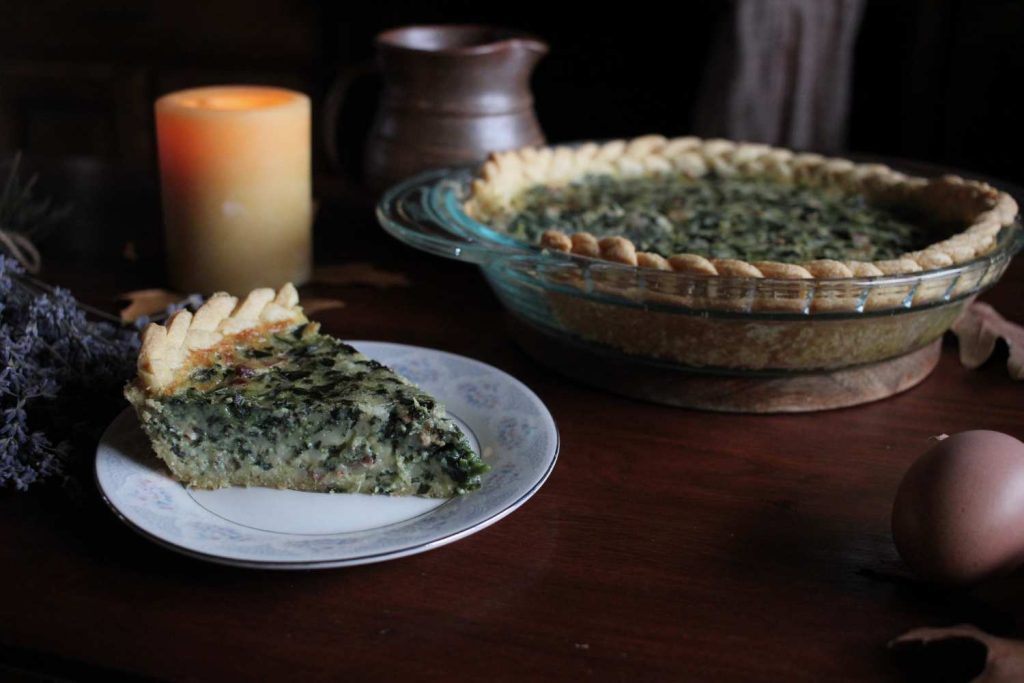 A close up picture of a slice of simple bacon and spinach quiche with braided pie crust.
